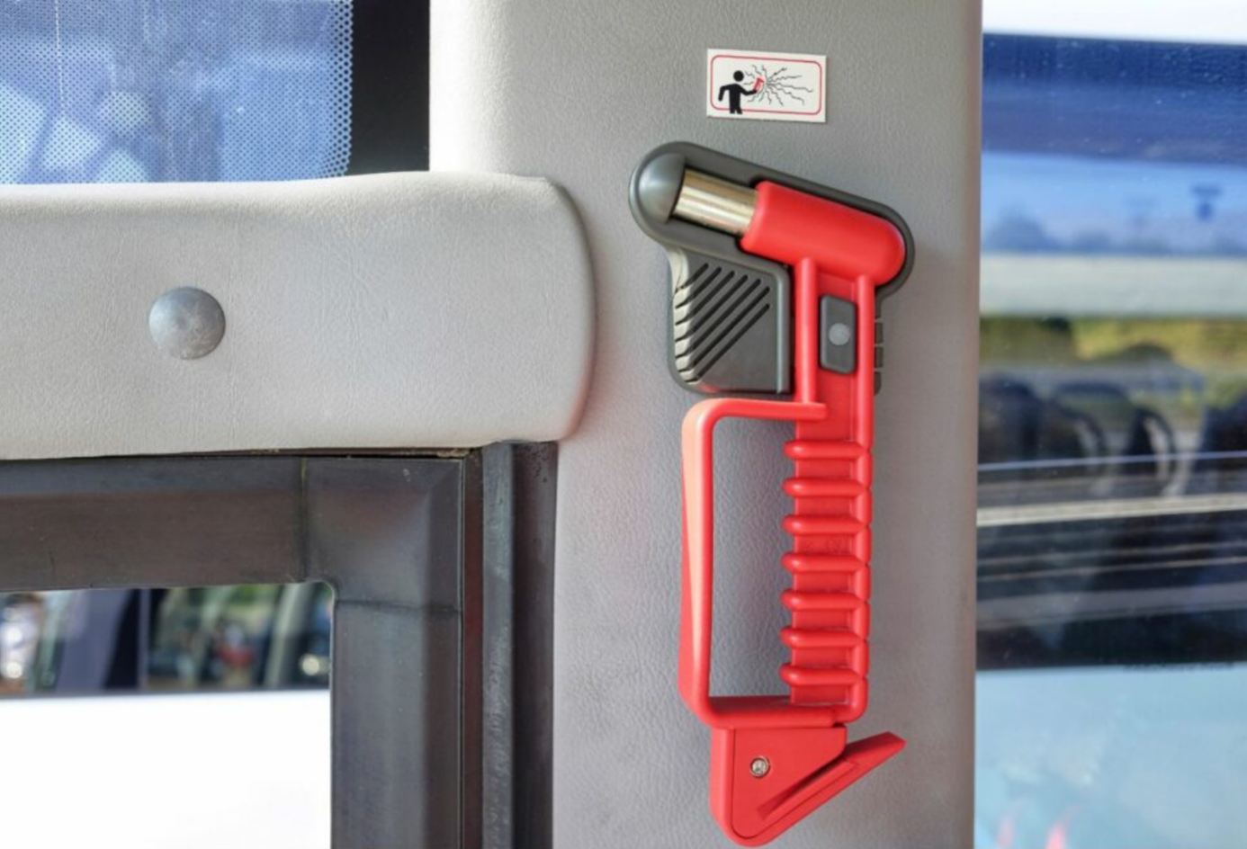 Marteau pic rouge installé près d’une issue de secours dans un bus, solution d’évacuation traditionnelle remise en question par l’évolution du règlement R107.