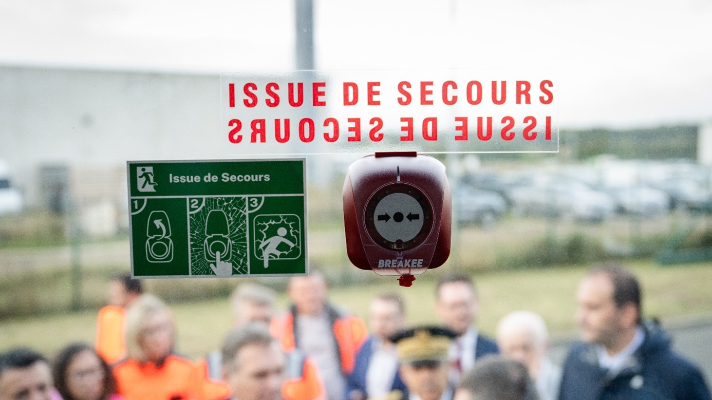 Brise-vitre électronique d’urgence BREAKEE rouge installé près d’une issue de secours dans un autocar